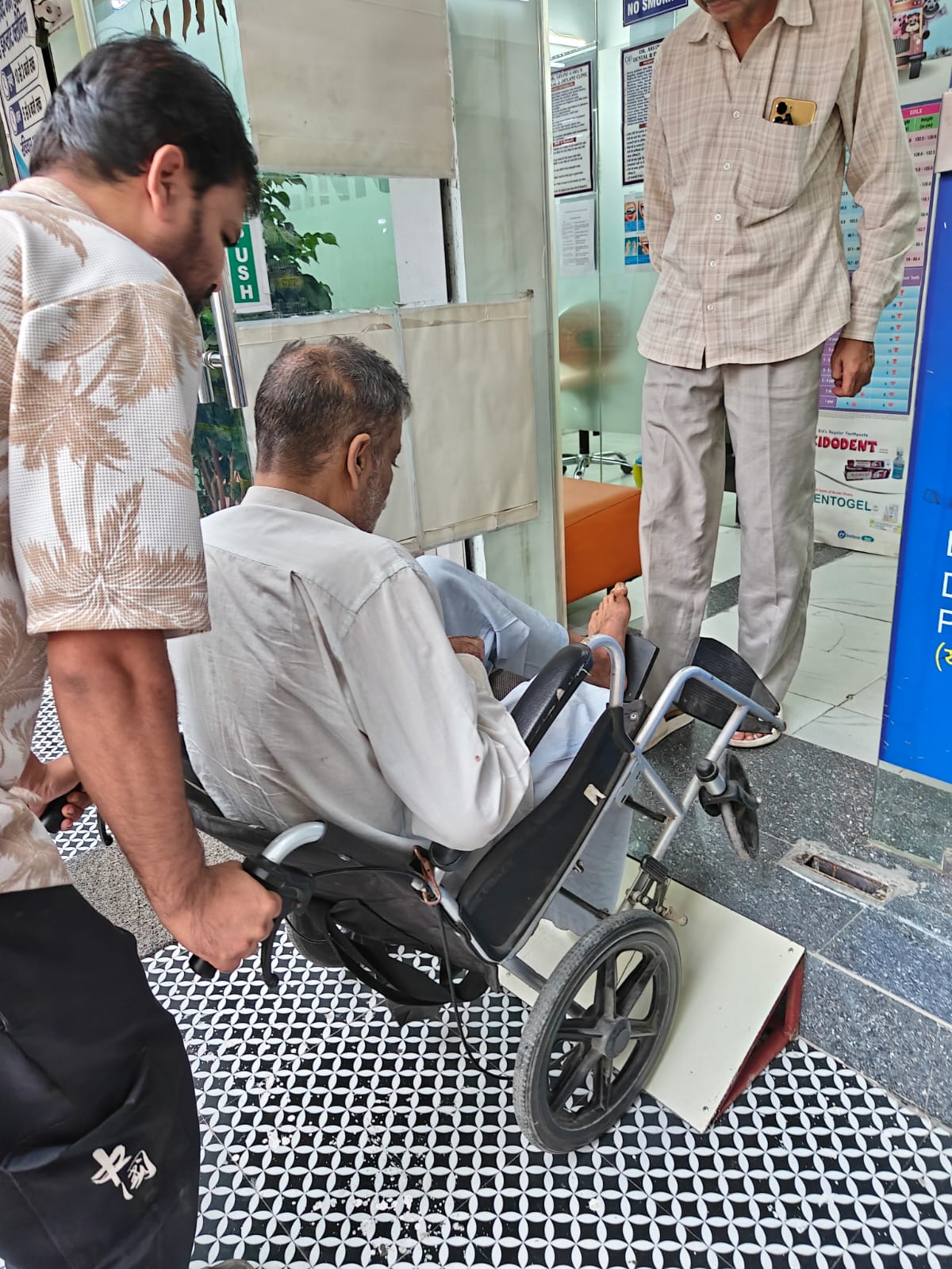 Wheelchair user being assisted over the clinic entrance ramp